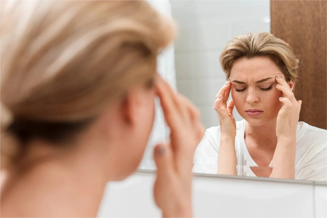 Woman looking tired and run-down in the mirror